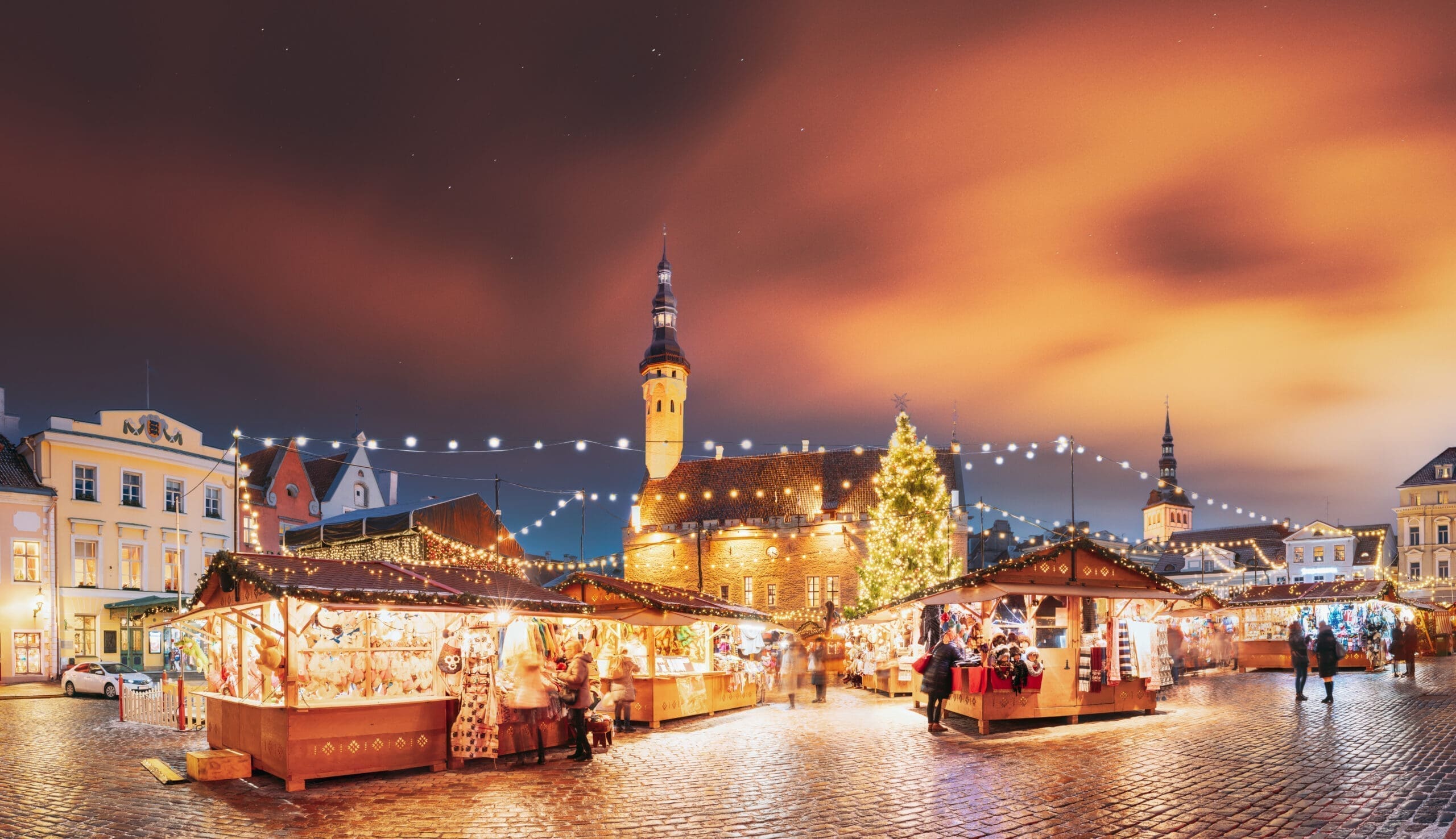 Tallinn, Estonia. Traditional Christmas Market On Town Hall Square. Trading Houses With Sale Of Christmas Gifts. Night Sky Above Famous Landmark. Altered Night Sky. Panorama, Panoramic View Sightseeing tours in Tallinn with IBG Travel